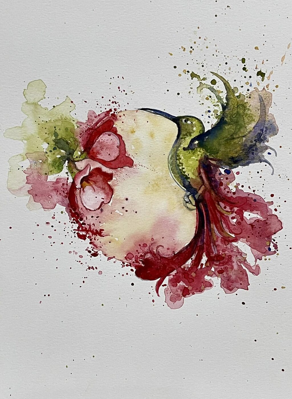Watercolor of a green hummingbird feeding at red blossoms, pigment splashing outward